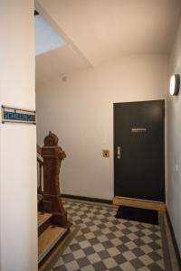 a hallway with a black door and a checkered floor at Schillinger-Berlin - dance, sleep, repeat! in Berlin