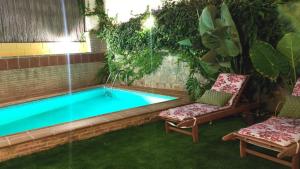 a swimming pool in a garden with two chairs next to it at Villa Granada Motril in Motril