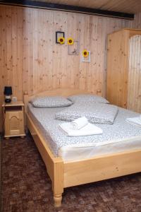 a bed in a room with a wooden wall at Pensiunea Casa Ioana in Şugag