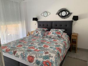 a bedroom with a bed with a floral bedspread and a mirror at Le Chant des Pierres - Entre Terre et Mer in Pornic