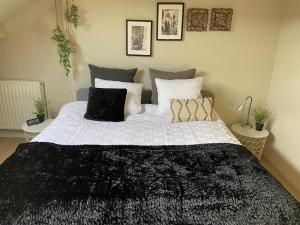 1 dormitorio con 1 cama grande con almohadas blancas y negras en escapade_Binchoise, en Binche