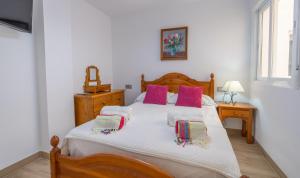a bedroom with a wooden bed with pink pillows at Shore Thing Playa in La Herradura
