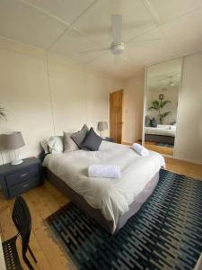 1 dormitorio con 1 cama grande y espejo en Wine Coast Cottage, Port Willunga, en Port Willunga