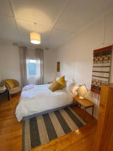 1 dormitorio con cama blanca y mesa en Wine Coast Cottage, Port Willunga, en Port Willunga