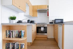 una cocina con armarios de madera y una estantería con libros. en Central Dover - 1 Bedroom apartment, en Kent