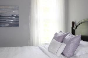 un letto con lenzuola e cuscini bianchi accanto a una finestra di Adair Park Bungalow ad Atlanta