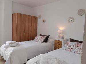 a bedroom with two beds and a wooden cabinet at Apartamento a Carballeira in Lugo