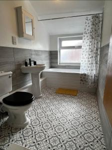a bathroom with a toilet and a sink and a window at 205a Monton Road in Manchester