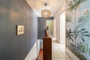 un couloir avec un mur bleu orné d'une peinture de palmiers dans l'établissement La Villa Morgabina - Haut standing- Piscine Chauffée - A St Pierre, à Saint-Pierre