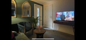 uma sala de estar com uma televisão de ecrã plano e um sofá em Stylish Scottish House with garden and parking em Perth