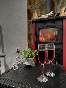 two glasses of wine on a table in front of a fireplace at Apartments Baron Žabljak in Žabljak