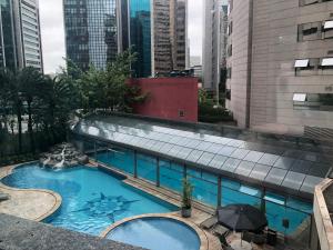 a swimming pool with an umbrella on a building at Flat Vila Olímpia ao lado do Shopping in Sao Paulo