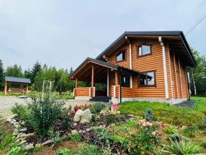 eine Blockhütte mit einem Garten davor in der Unterkunft Шале Вілія in Worochta