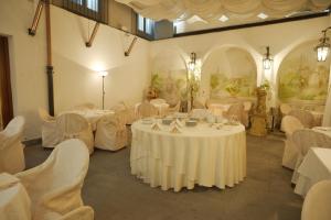 um salão de banquetes com mesas brancas e cadeiras brancas em Hotel del Real Orto Botanico em Nápoles