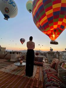 a woman standing on a roof looking at hot air balloons at Naraca Cave House in Goreme