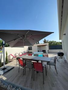 un patio con mesa, sillas y sombrilla en Magnifique villa avec piscine extérieure, en Alleins