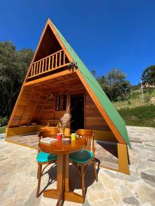 ein kleines Haus mit einem Tisch und Stühlen davor in der Unterkunft Chalé do Portal in Monte Verde
