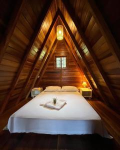 1 dormitorio con 1 cama blanca en el ático en Chalé do Portal en Monte Verde