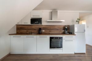 uma cozinha com armários brancos e um balcão de madeira em Gemütlich 5 em Wissembourg