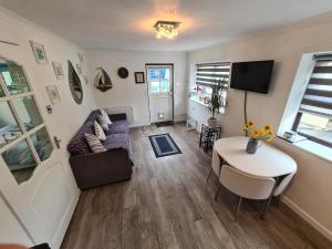 a living room with a couch and a table at Knobbly Nook, whole property, gardens, parking, wifi, relaxing near Eden Project and coast in Saint Blazey