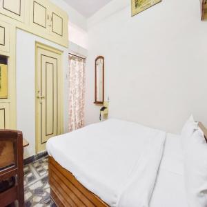 ein Schlafzimmer mit einem weißen Bett und einer Tür in der Unterkunft Datta Guest House By WB Inn in Bharatpur