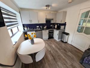 a kitchen with a white table and a vase of flowers at Knobbly Nook, whole property, gardens, parking, wifi, relaxing near Eden Project and coast in Saint Blazey