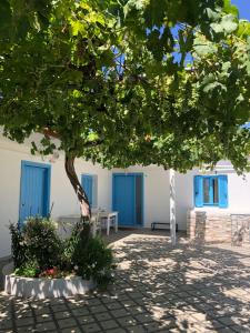 ein Baum vor einem weißen Gebäude mit blauen Türen in der Unterkunft Acrotel Sofia's Guest House in Sidherás