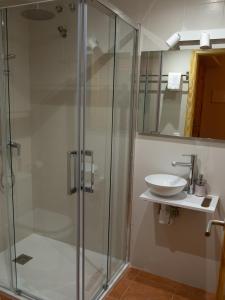 uma casa de banho com uma cabina de duche em vidro e um lavatório. em El Descanso del Sol - Apartamento en Pirineos em Plan