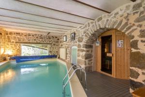 a pool in a house with a stone wall at Le Berthoir in Pélussin