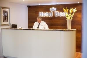 Een man aan een balie in een hotelkamer. bij Hotel Boss in Łódź