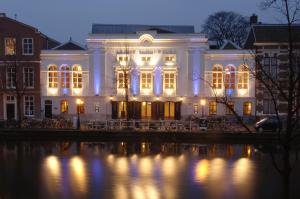 um edifício iluminado à noite ao lado de uma massa de água em Golden Tulip Leiden Centre em Leiden