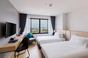 a hotel room with two beds and a desk and a television at Best Western Nada Don Mueang Airport hotel in Bangkok
