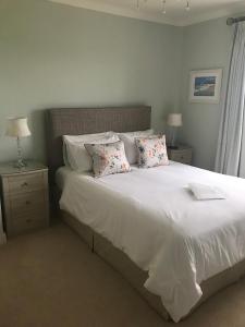 Schlafzimmer mit einem Bett mit weißer Bettwäsche und Kissen in der Unterkunft Tregiffian Farm B&B in Penzance