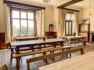 a dining room with wooden tables and benches at Nethercott House in Winkleigh