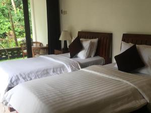 dos camas sentadas una al lado de la otra en un dormitorio en Raka Rai Bungalows, en Ubud