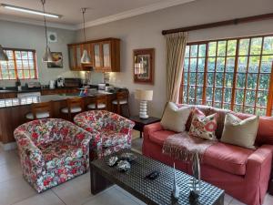 een woonkamer met een rode bank en stoelen bij Pearl Cottage in Durban