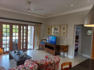 een woonkamer met een bank en een tv bij Pearl Cottage in Durban