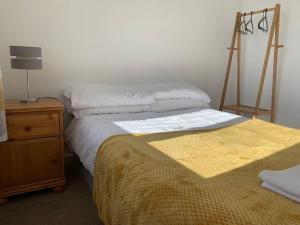 a bedroom with a bed and a dresser with a lamp at Modern & Light with Sea Views & Parking, Swansea in Dunvant