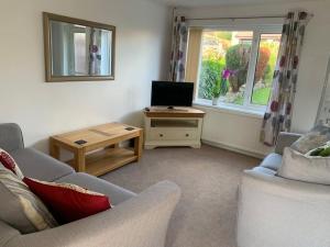 a living room with a couch and a table with a television at Modern & Light with Sea Views & Parking, Swansea in Dunvant