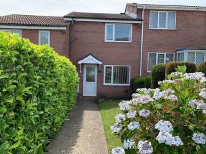 a brick house with a white door and some flowers at Modern & Light with Sea Views & Parking, Swansea in Dunvant