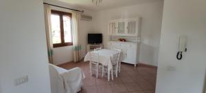 cocina blanca con mesa y ventana en Case Vacanza Aiosardegna, en Pula