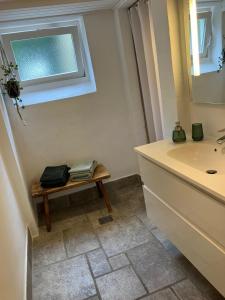 baño con lavabo y banco con espejo en Brøndums Bed & Breakfast, en Hjørring