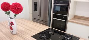 a kitchen with a stove and a vase with red flowers at Modern two bedroom house near beach/ Durham City in Hawthorn