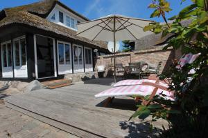 a wooden deck with a chair and an umbrella at Alte Scheune in Ahrenshoop +17 photos