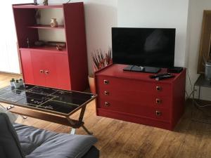 czerwona komoda z telewizorem z płaskim ekranem na górze w obiekcie Studio Cosy à Woluwé w Brukseli