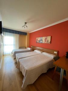 1 dormitorio con 2 camas y pared roja en Hostal Santiago 2 en Burgos