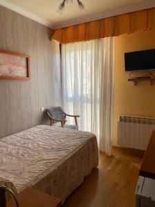 1 dormitorio con 1 cama, TV y ventana en Hostal Santiago 2, en Burgos