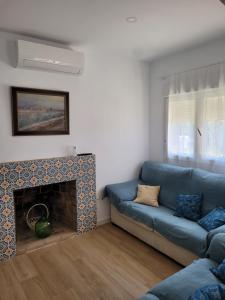 a living room with a blue couch and a fireplace at Casa cerca de Sevilla con piscina in Valencina de la Concepción