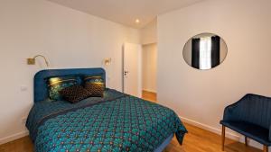 Dormitorio con cama con edredón verde y espejo en L'art déco, T3 Terrasse, classé meublé de tourisme en Rodez
