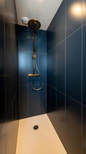 y baño con ducha de azulejos azules. en L'art déco, T3 Terrasse, classé meublé de tourisme en Rodez